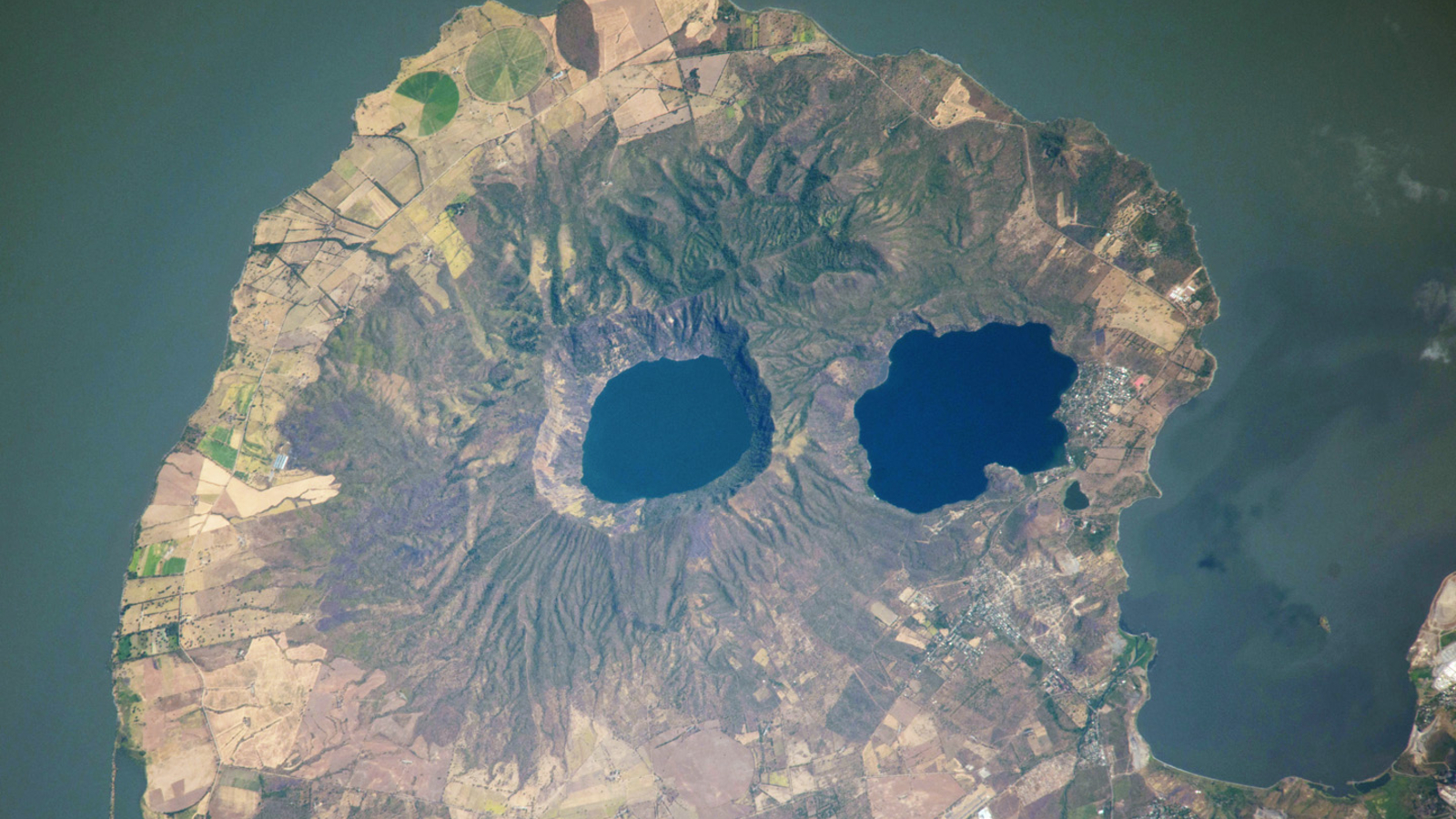 Volcanic “squeaky eyes” stare at space from a skull-like peninsula – Earth from space
